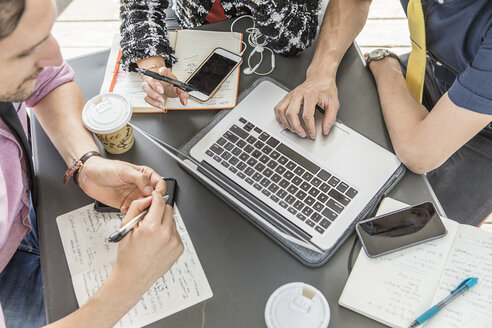 Ausgeschnittene Aufnahme eines Geschäftsteams, das bei einem Treffen im Café einen Laptop benutzt - ISF03268