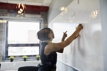 Zwei Frauen im Büro, Brainstorming, Klebezettel auf Whiteboard - ISF03274