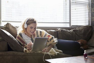 Frau benutzt digitales Tablet auf Sofa - ISF03280