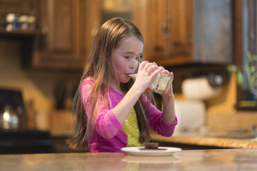 Junges Mädchen trinkt Milch am Küchentisch - ISF03316