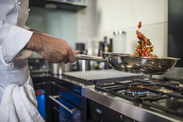 Koch hält Bratpfanne, kocht Essen auf dem Herd, Nahaufnahme - ISF03343