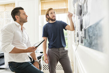 Young male designer explaining mood board idea to colleague in creative studio - ISF03353