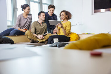 Digitaldesigner auf dem Bürosofa mit Blick auf ein digitales Tablet - ISF03398