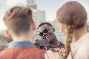 Junger Mann fotografiert Freunde auf einer Dachparty in London, UK - ISF03423