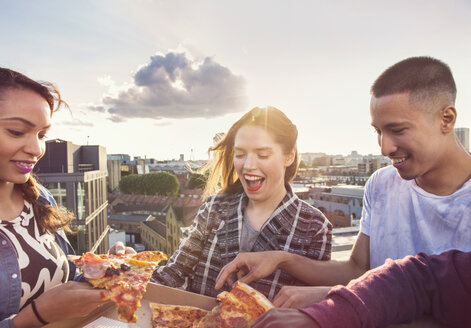 Young adult friends sharing pizza at roof party in London, UK - ISF03428