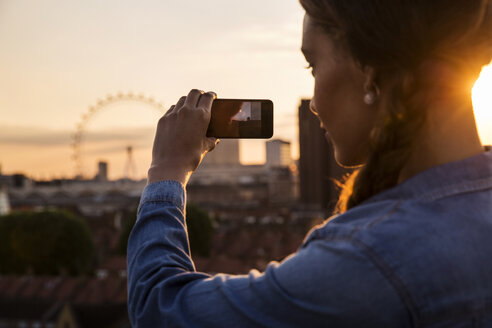 Junge Frau fotografiert Skyline bei Sonnenuntergang Dach Party in London, UK - ISF03432