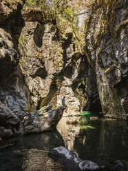 Mid adult tourist sitting on rock looking at river Azul gorge, Cajon del Azul near El Bolson, Patagonia, Argentina - ISF03477