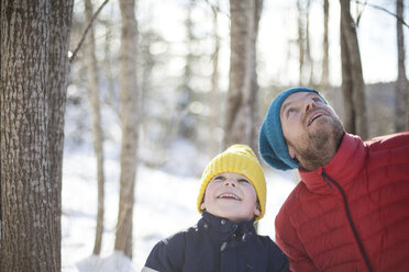 Man and son looking up from snow covered forest - ISF03506