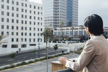 Young man leaning on railings, looking at office building - ISF03553
