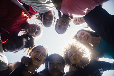 Low angle view of schoolgirl soccer team huddled in circle - ISF03564