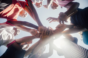 Low angle view of schoolgirl soccer team in circle with hands together - ISF03565