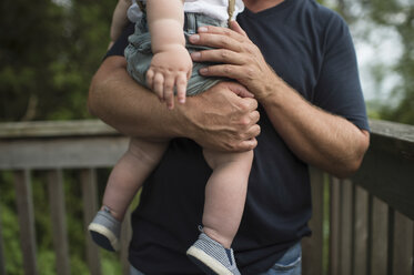 Mittelteil eines Mannes, der seinen kleinen Sohn auf dem Balkon trägt - ISF03643