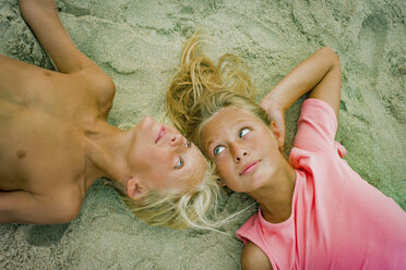 Overhead-Porträt eines blonden Bruders und einer blonden Schwester, die sich am Strand gegenüberliegen - ISF03646