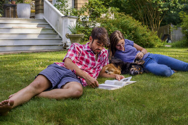 Paar auf Gras im Garten mit Hund, lesend - ISF03651