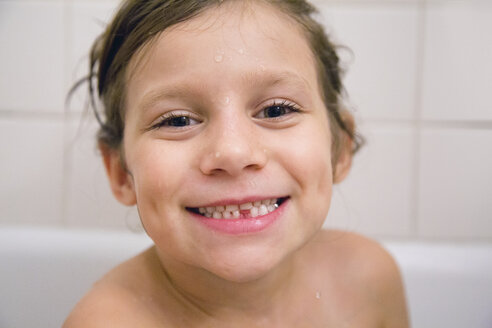 Porträt eines Mädchens mit fehlendem Zahn im Bad, das lächelnd in die Kamera schaut - ISF03657