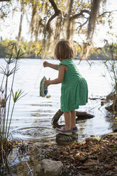 Girl playing with toy boat in lake, Orlando, Florida, United States, North America - ISF03667