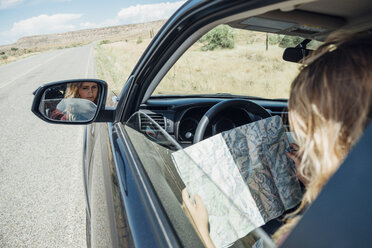 Blick über die Schulter einer Frau, die im Auto sitzt und auf eine Karte schaut - ISF03672