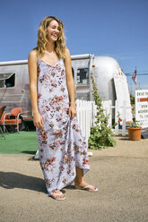 Young woman in maxi dress laughing by airstream coffee shop - ISF03680