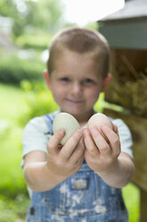 Boy holding hens eggs looking at camera smiling - ISF03720