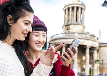 Two young stylish women looking at smartphone, London, UK - ISF03725