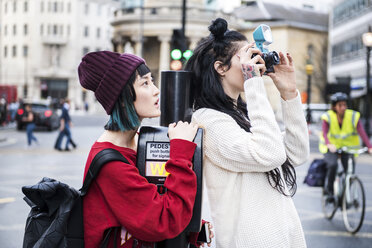 Zwei junge stilvolle Frauen fotografieren auf der Straße, London, UK - ISF03726
