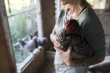 Frau hält Huhn im Hühnerstall - ISF03762