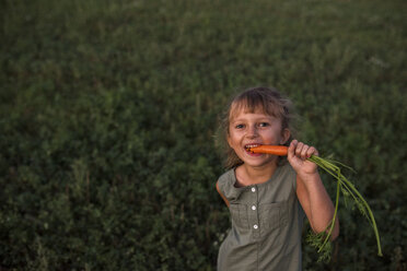 Porträt eines jungen Mädchens, das eine frisch gepflückte Möhre isst - ISF03781