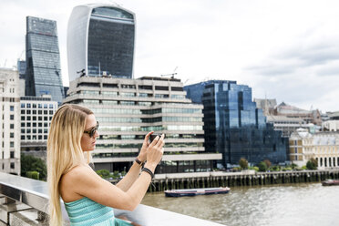 Weibliche Touristin steht auf der London Bridge und fotografiert die Aussicht - ISF03784