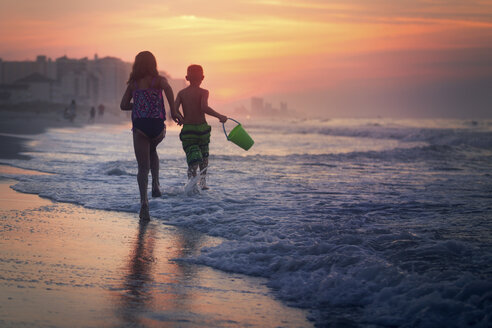 Geschwister paddeln im Meer bei Sonnenuntergang, North Myrtle Beach, South Carolina, Vereinigte Staaten - ISF03792