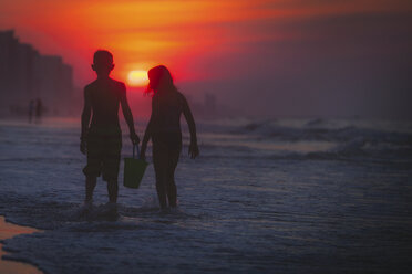 Geschwister paddeln im Meer bei Sonnenuntergang, North Myrtle Beach, South Carolina, Vereinigte Staaten - ISF03793