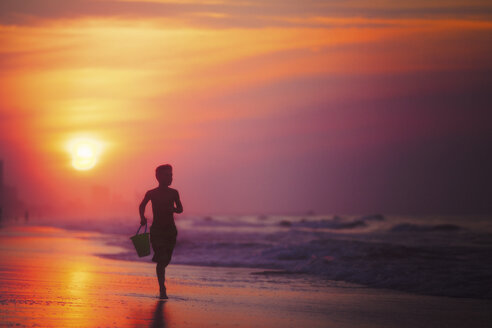 Silhouette eines Jungen, der bei Sonnenuntergang am Strand läuft, North Myrtle Beach, South Carolina, Vereinigte Staaten - ISF03794