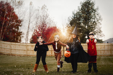 Portrait of boy and girls posed in halloween costumes in garden at sunset - ISF03815