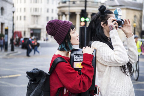 Zwei junge stilvolle Frauen fotografieren auf der Straße, London, UK, lizenzfreies Stockfoto