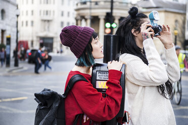 Zwei junge stilvolle Frauen fotografieren auf der Straße, London, UK - ISF03824