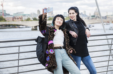 Zwei junge stilvolle Frauen machen ein Smartphone-Selfie auf der Millennium-Fußgängerbrücke, London, UK - ISF03826