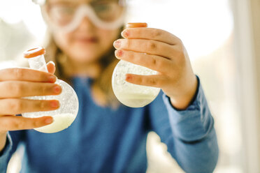 Girl doing science experiment, holding flasks of liquid - ISF03867