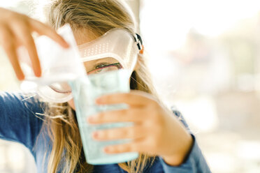 Girl doing science experiment, pouring liquid - ISF03868