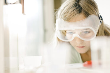 Girl doing science experiment, watching through safety goggles - ISF03869