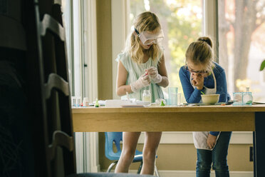 Two girls doing science experiment, reading chemistry set instructions - ISF03875