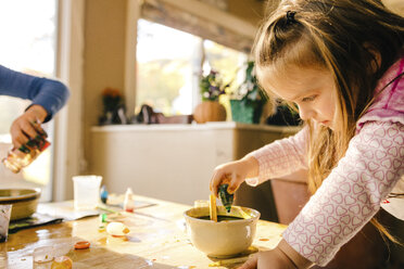 Girl doing science experiment, dropping green liquid into bowl - ISF03882