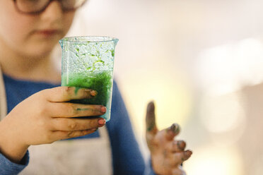 Girl doing science experiment, holding flask of green liquid - ISF03885