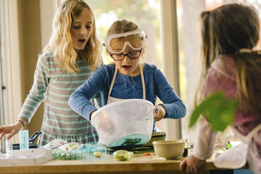 Girls doing science experiment, mixing green liquid in bowl - ISF03886
