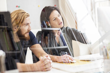 Male and female designer looking at computer in creative studio - ISF03914