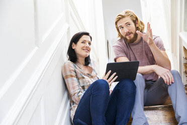 Male designer explaining idea to colleague on creative studio stairway - ISF03924