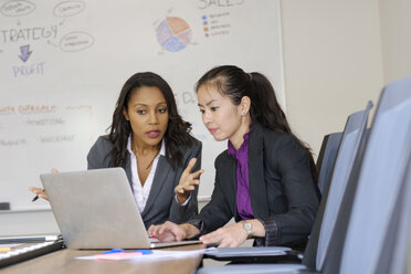 Zwei Geschäftsfrauen im Büro, die auf einen Laptop-Bildschirm schauen - ISF03970