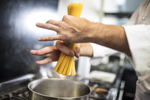 Koch legt Spaghetti in einen Topf auf dem Herd, Nahaufnahme, Draufsicht - ISF03988