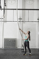 Frau beim Seilklettern in einer Cross-Trainingshalle - ISF04062