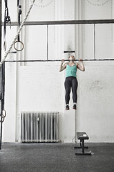 Frau beim Klimmzug im Fitnessstudio für Cross-Training - ISF04063