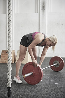 Woman adjusting barbell in cross training gym - ISF04070