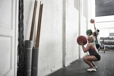 Freunde werfen Fitness-Ball gegen die Wand im Cross-Training-Fitnessstudio - ISF04073